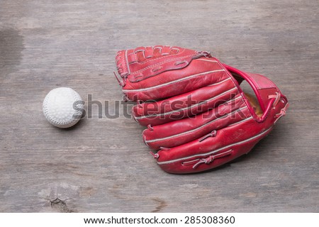 Old leather baseball glove with baseball on wood background