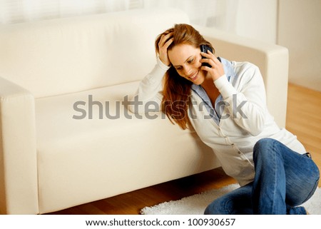 Portrait of a young friendly woman having fun on mobile phone at home