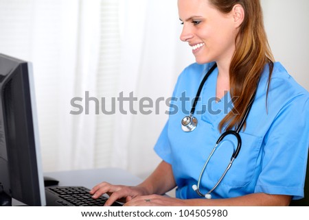 Portrait of a blonde friendly young nurse looking to computer screen at hospital