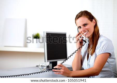 Portrait of a friendly blonde secretary speaking on phone at customer service office