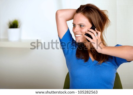 Portrait of a blonde friendly young woman  conversing on cell phone while is looking to the right