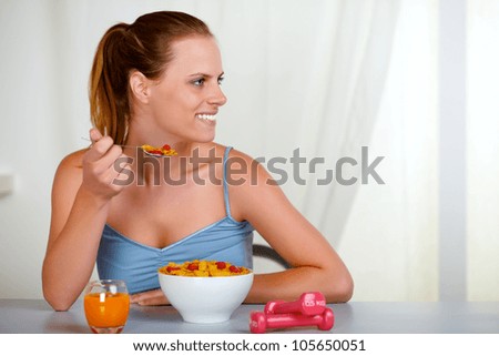 Portrait of a beautiful young woman looking to the right and eating healthy meal at home indoor