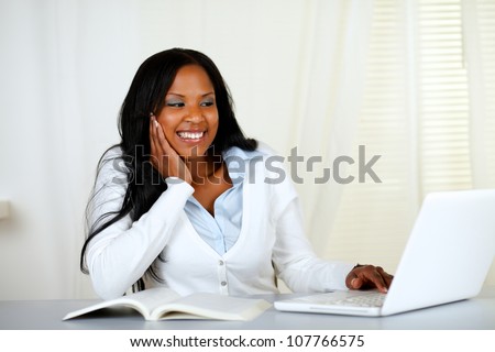 Portrait of a lovely relaxed student woman smiling and looking to a laptop at home indoor
