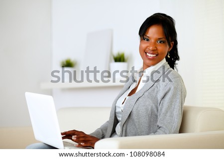 Portrait of a happy woman browse the Internet on laptop while is sitting on sofa at home
