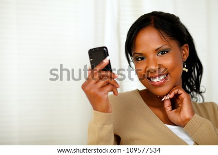 Portrait of a sophisticated lady reading a message on cellphone while looking at you