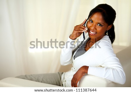 Portrait of a beautiful young woman looking at you while conversing on phone. With copyspace