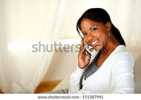 Portrait of a charming young woman looking at you while conversing on phone. With copyspace