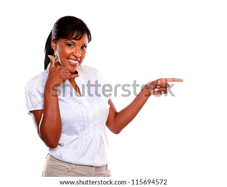 Smiling female looking at you and pointing left while saying call me on isolated background