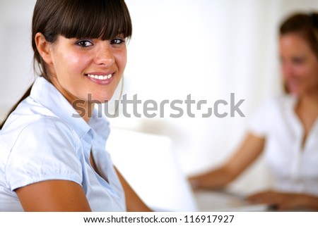 Hispanic adult businesswoman looking and smiling at you at office