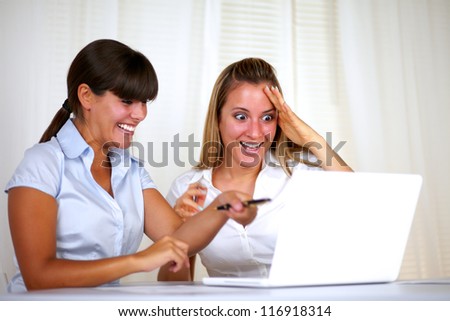 Surprised and excited young businesswomen reading on laptop at office