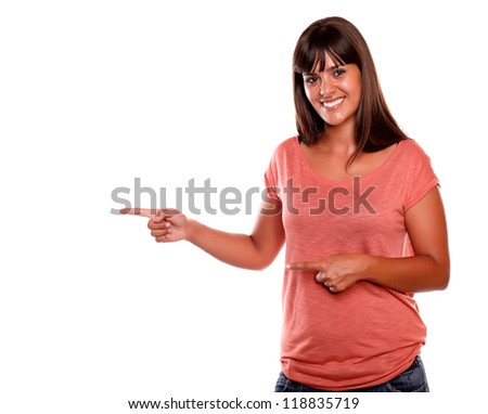 Stylish young woman looking at you while pointing to her right - copyspace