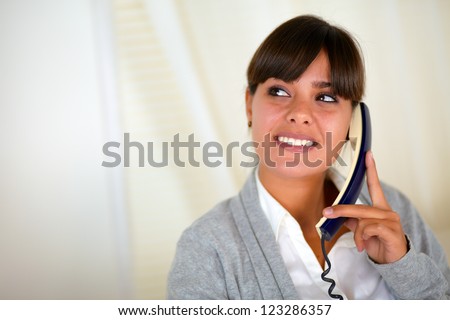 Portrait of a hispanic young woman speaking on phone and looking to her right up - copyspace