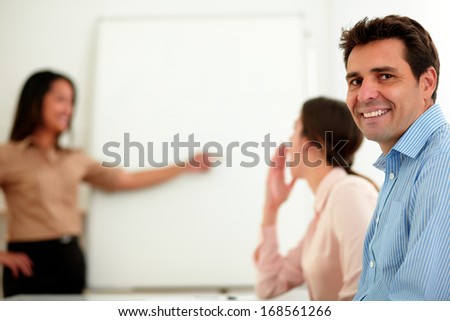 Portrait of an adult businessman on blue shirt smiling and looking at you during a conference with colleagues on office