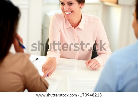 Portrait of young female bank manager working on agreement contract and explaining the application form to a young woman at office