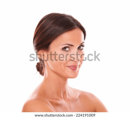 Head and shoulders portrait of pretty adult female showing her freshness while smiling at camera with nude shoulders on isolated studio