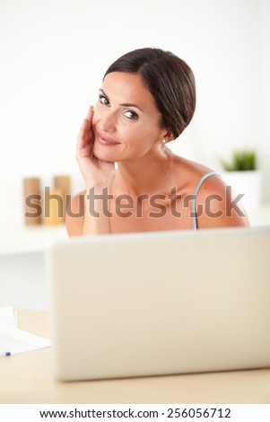 Sophisticated woman in blue blouse working on her laptop in her house
