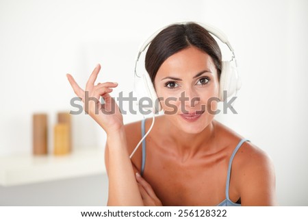 Smart woman in blue blouse listening to music on headphones in her house