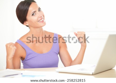 Lovely lady in purple shirt surfing the web and celebrating a success at home
