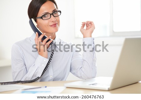 Adult secretary with glasses talking on the phone while smiling in her office