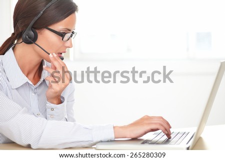 Adult female secretary with headphones doing customer service in a callcenter