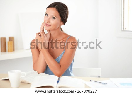 Attractive young woman in blue blouse studying her books while sitting - copyspace