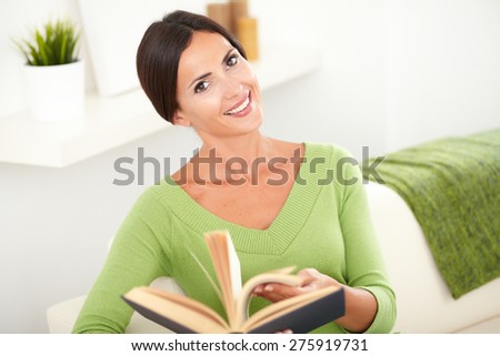 Beautiful caucasian woman with straight hair browsing a book while looking at the camera