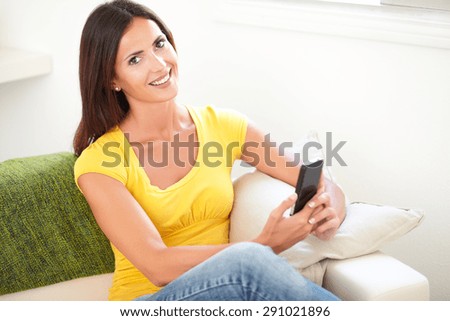 Attractive woman holding a cell phone while looking at the camera