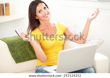 Carefree woman using a credit card and a laptop for electronic payment
