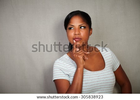 Waist up portrait of a young african woman thinking with hand on chin - copy space