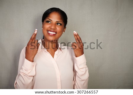 Young businesswoman in button down shirt crossing fingers while smiling - copy space