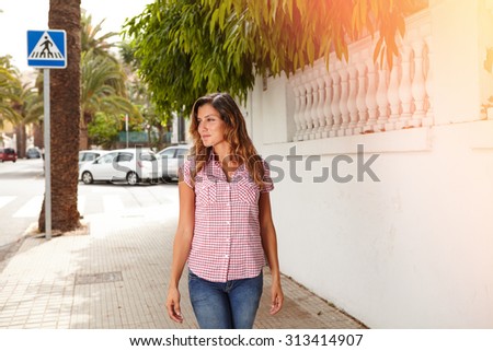 Young woman in brightly lit day smiling while walking outdoors - copy space