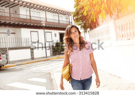 Beautiful young woman 20-24 years old walking down the street and looking at the camera