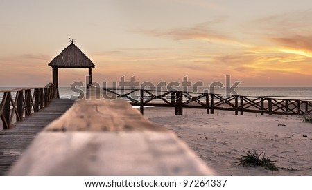 a boardwalk to the beach at sunset