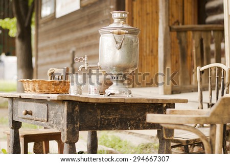 Antique russian samovar and other items for tea on an old wooden table in the garden. The museum exposition.