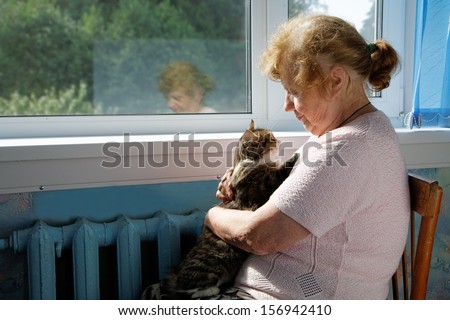 The old woman holds cat in a lap