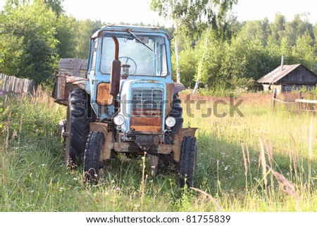 Old wheel tractor with the trailer against wood
