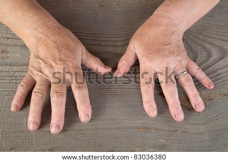 Hands of the old woman on a table from unplaned boards