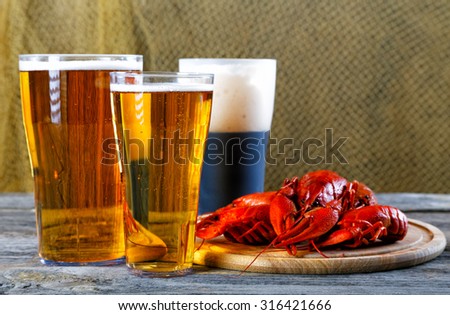Tasty boiled crayfishes and beer on old table