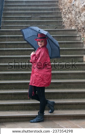 Young happy pretty woman standing in the rain with an umbrella.