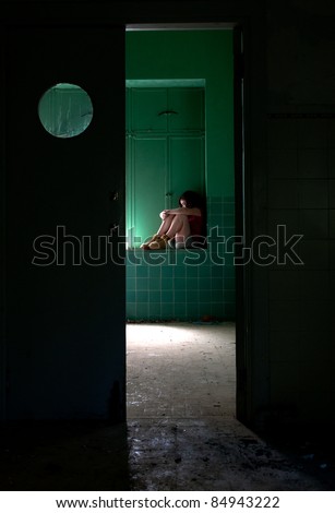 Teen in depression sitting in an empty abandoned room.