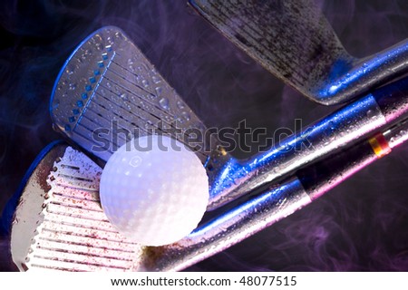 Old golf clubs with  ball on black background