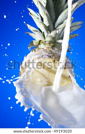 Pineapple with splashing milk on blue background