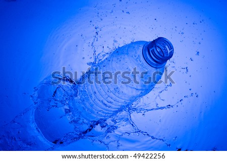 Plastic bottle in water. Creative splashing blue water