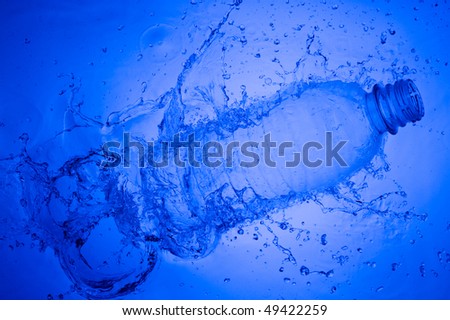 Plastic bottle in water. Creative splashing blue water