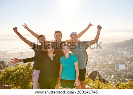 Happy group of student hikers smiling joyfully and posing together while hiking a nature trail on a mountain