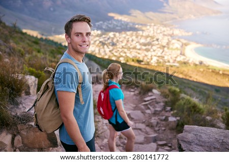 Handsome male student looking positively at the camera while pausing on a nature trail during an early morning hike