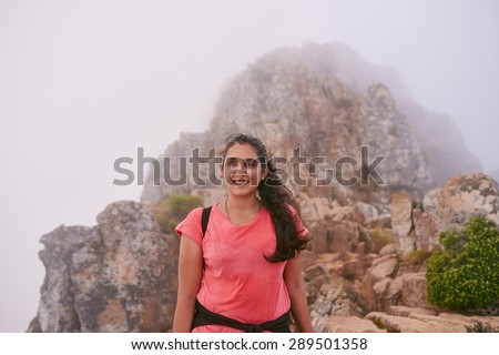 Portrait of a happy woman standing on a mountain top on a misty morning