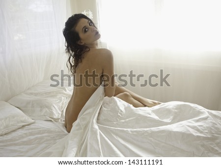 beautiful nude girl on a bed of white satin