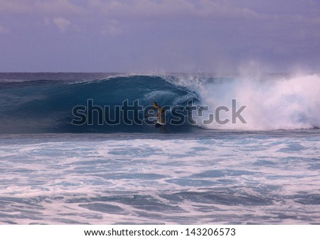 young woman on surfboard riding a big wave in hawaii