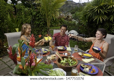 friends enjoying a barbecue lunch in a tropical garden